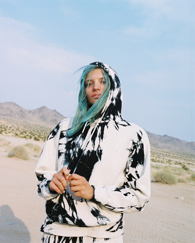 A model with blue hair wearing a tie dye, black and white hoodie by designer Esper for the brand Com...
