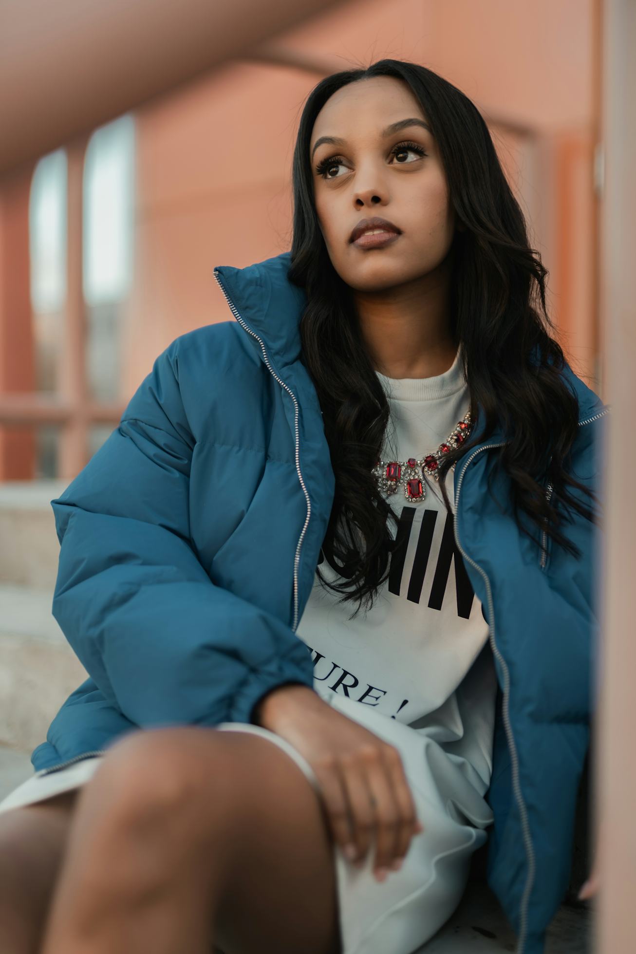 A portrait of Ruth B in a blue buffer jacket and white T-shirt dress.