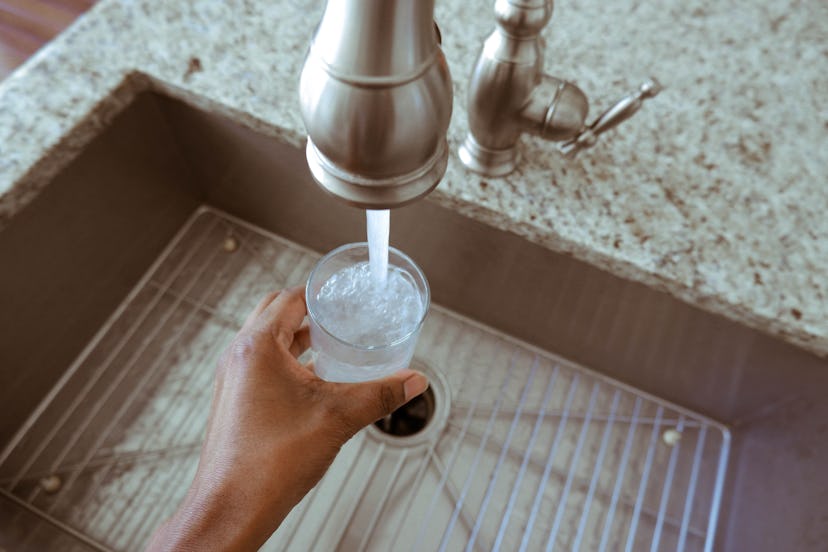 closeup of hand filling up a glass of water at sink