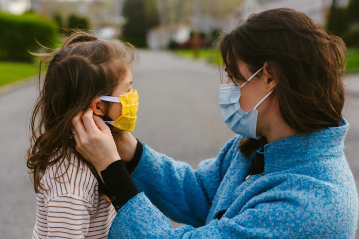 Mother wearing mask adjusts mask on small child