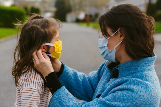Mother wearing mask adjusts mask on small child