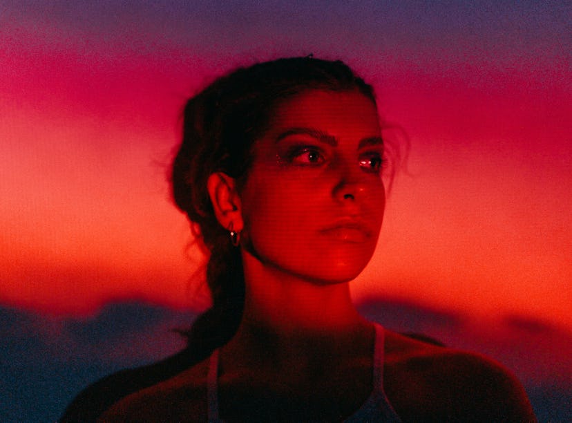 Young woman in neon red light during the May 2021 full blood moon, total lunar eclipse.