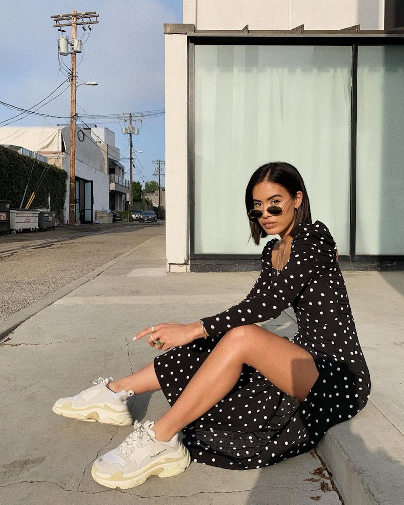 Jill Wallace wears chunky white sneakers paired with a romantic puff-sleeve black dress with white d...