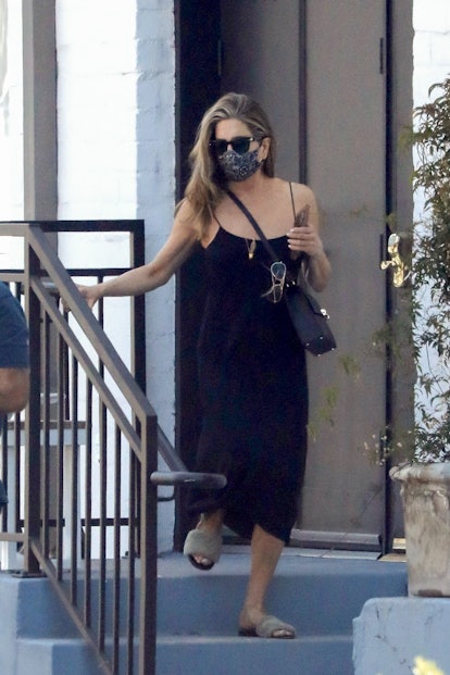Jennifer Aniston leaves a hair salon in Beverly Hills while wearing a black slip dress and fuzzy sli...