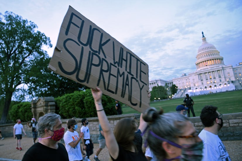 Protesters marching outside the U.S. Capitol in Washington with a sign that says "Fuck White Suprema...