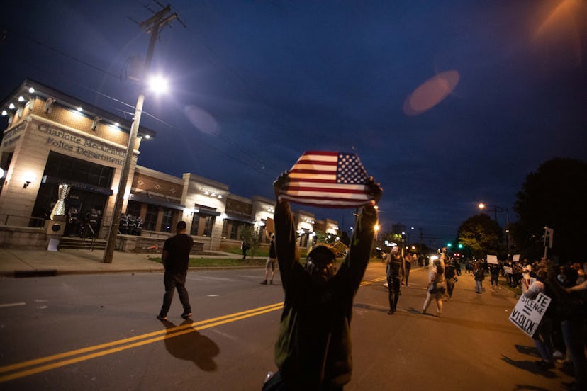 A man holding up a U.S. flag during a protest in Charlotte