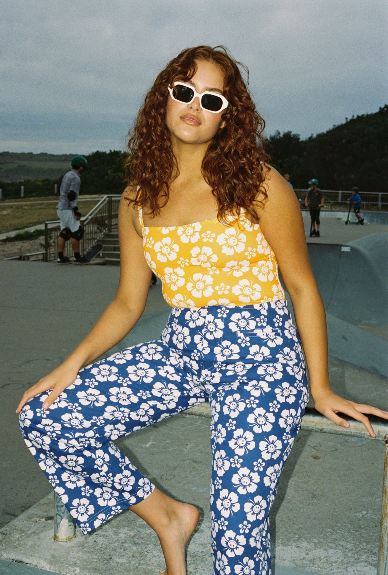 A woman wearing yellow shirt and blue pants inspired by Hawaiian prints, surf culture and a 2006 mov...