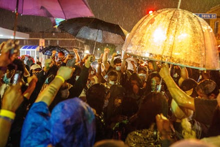 Protesters gathering in the rain in Minneapolis with umbrellas and rain coats