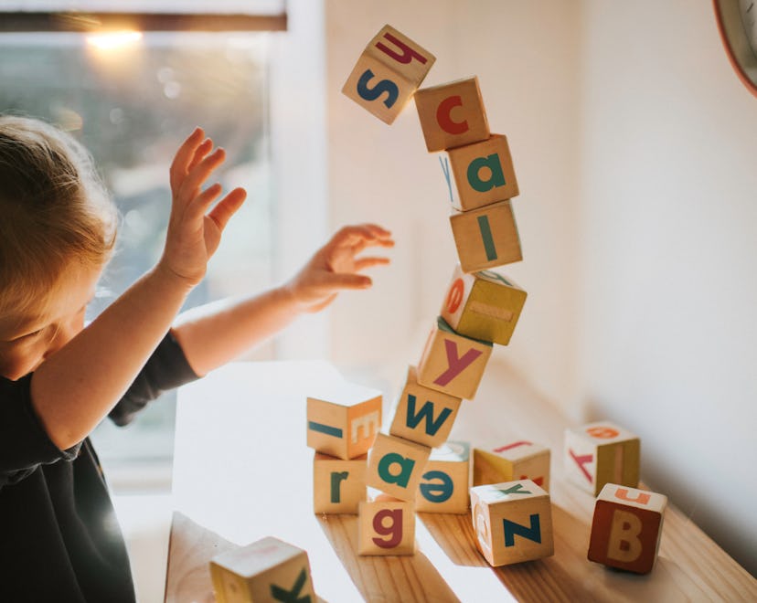 child knocking down blocks that spell out scallywag