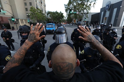A man holding his hands up in front of police during a protest in Oakland