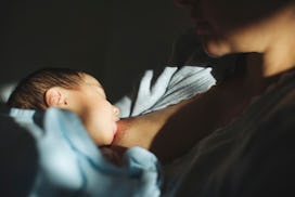 close up of baby breastfeeding in dim room 