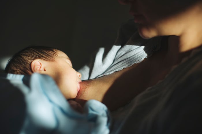 close up of baby breastfeeding in dim room