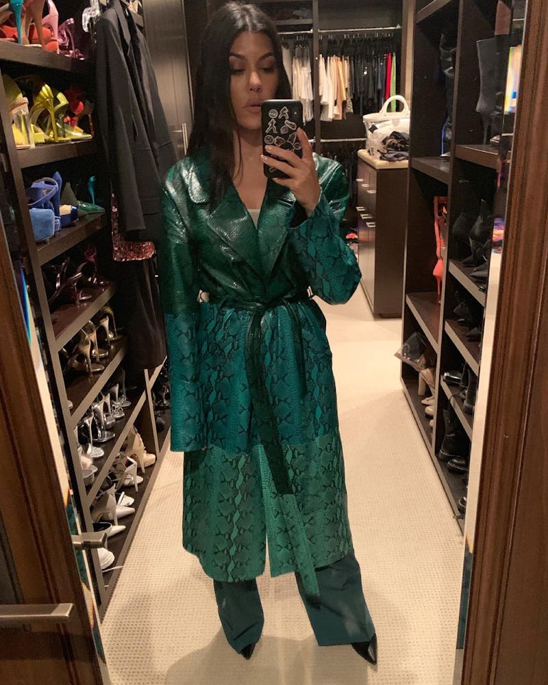 Kourtney Kardashian wearing a green snakeskin trench coat.