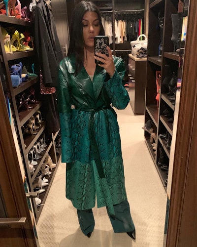 Kourtney Kardashian wearing a green snakeskin trench coat.