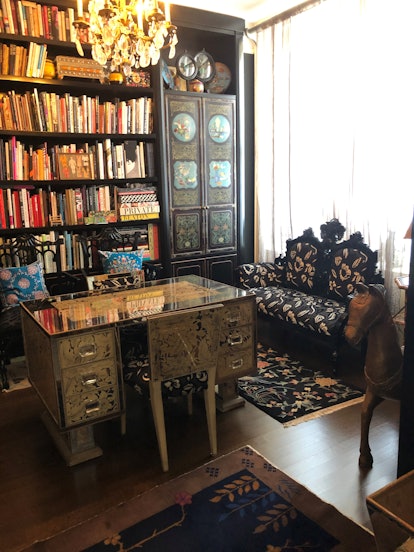 Home office of Anna Sui with big book shelfs, a wooden working table, and a black seater sofa