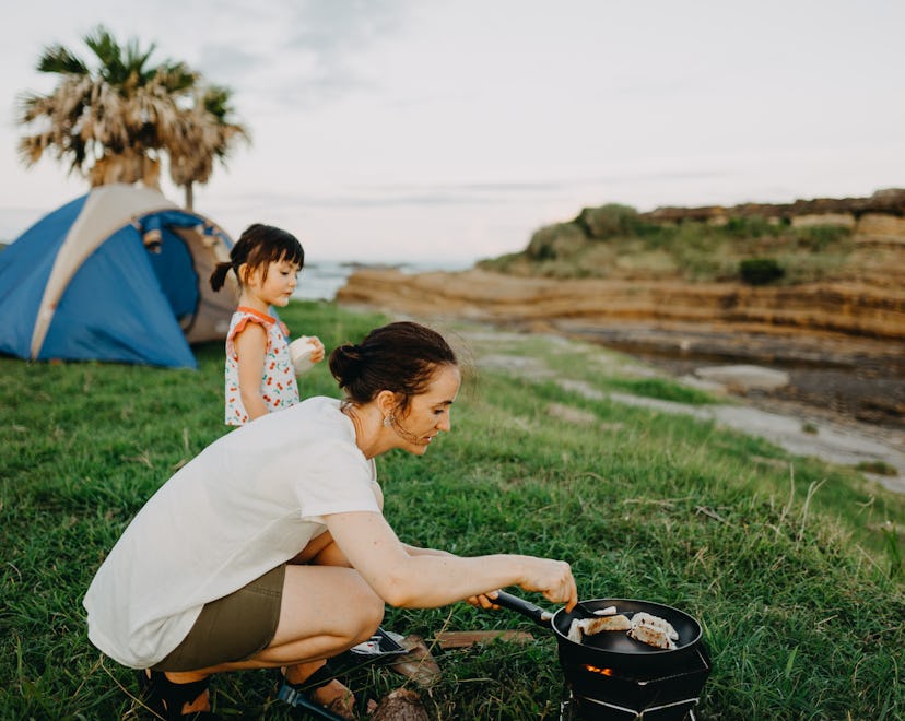 A mother preparing a meal while camping with kids