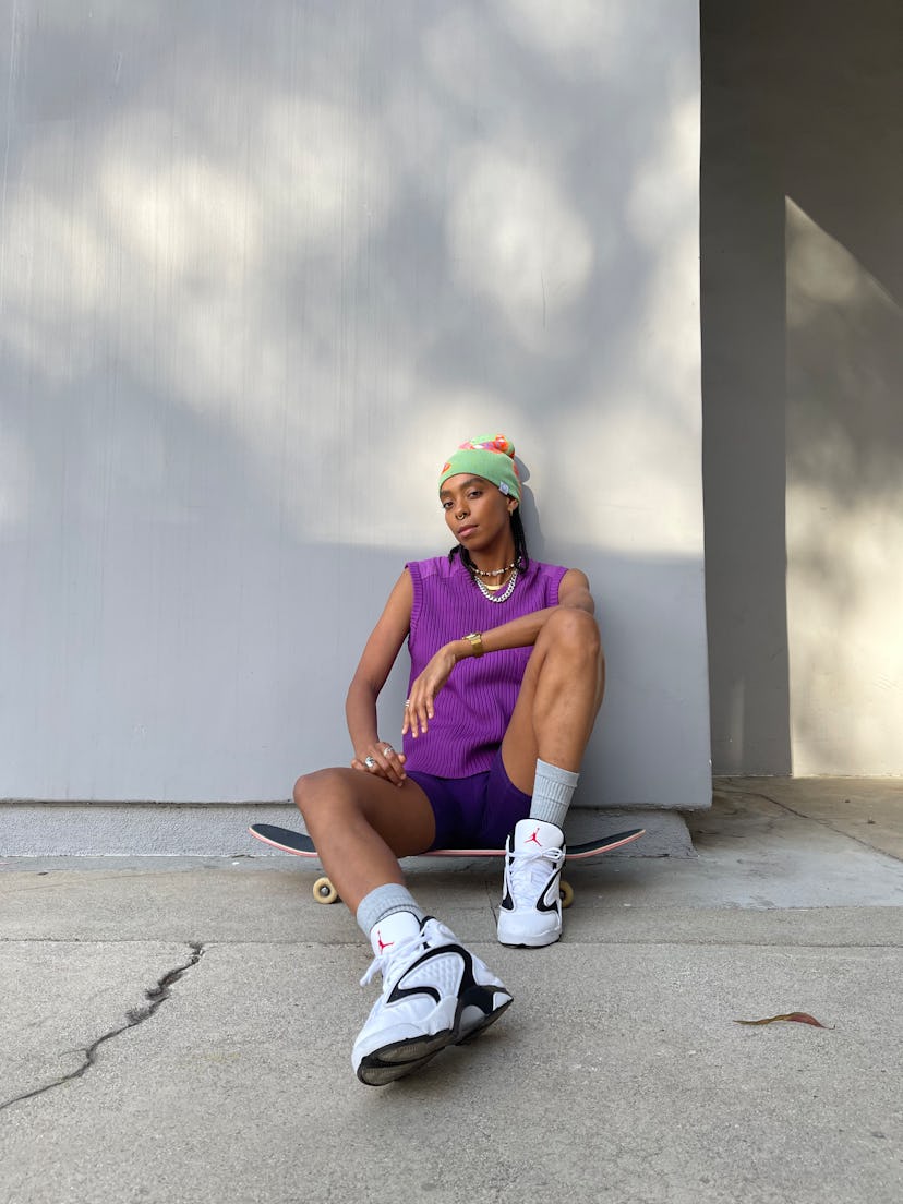 Skater and model Briana King sitting on her skateboard in a purple Heaven by Marc Jacobs  vest and g...