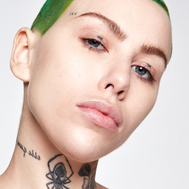 A model with tattoos and green hair modeling Kosas Tinted Face Oil, one of several skin tints that a...