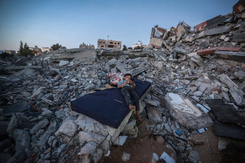 Palestinian boy lying on the ruins of his destroyed home in Beit Hanoun