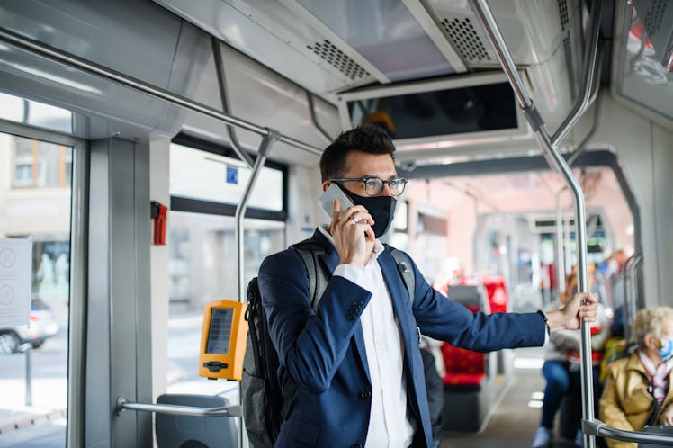 Man holds railing on bus