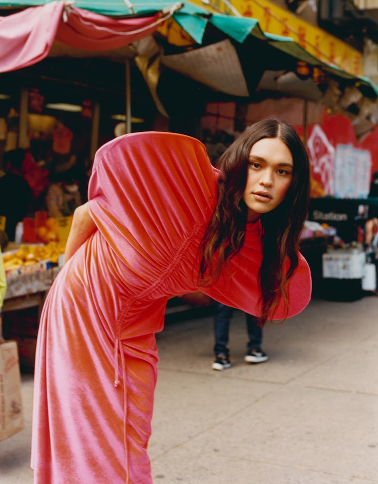 Charlie Nishimura in a long, tight, pink dress with an emphasis on the circular shoulders