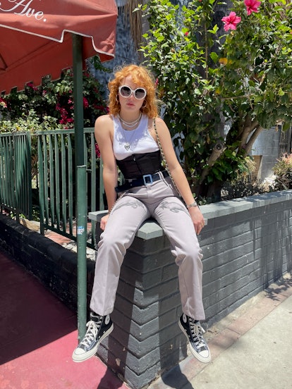 Musician Mallory Merk sitting on a brick wall in Basketcase Custom Dickies a white Hanes top and a b...
