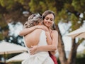 Young woman hugging her sister on her wedding day before taking Instagram pictures.