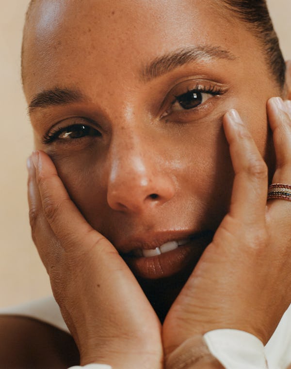 A closeup beauty shot of Alicia Keys touching her face 