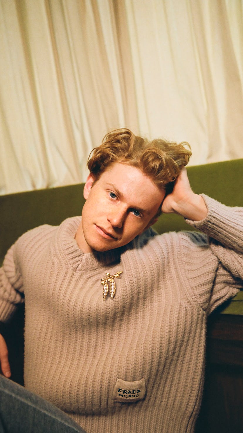 Gem chef Flynn McGarry poses in a brown sweater on a couch for Bustle's food issue cover.