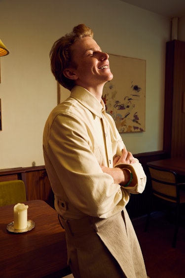 Gem chef Flynn McGarry wears Bottega Veneta while leaning against a table and smiling.