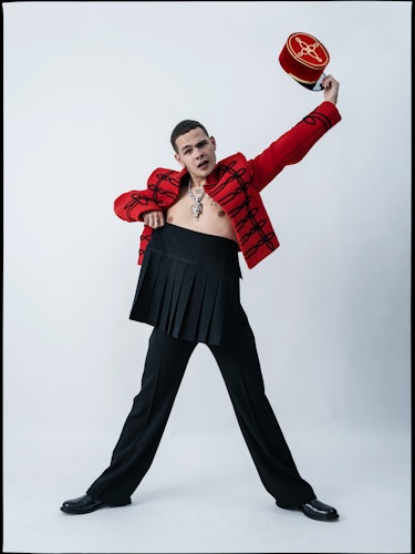 Slowthai wears a Louis Vuitton Men’s jacket, skirt, and pants; vintage hat from the Costume Studio, ...