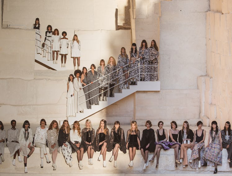 Several models sitting and standing on stairs at the Chanel Cruise 2021 show