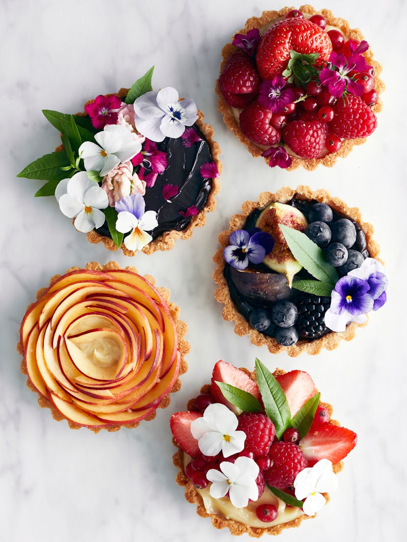 Five fruit tarts in various flavors; garnished with fresh flowers