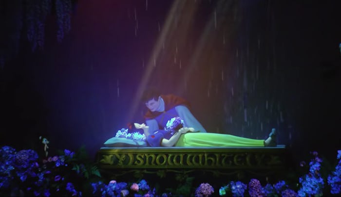Snow White lies sleeping under an enchanted spell as her Prince Charming looks over her in a scene f...