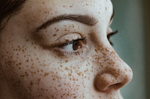 Young woman closeup on brows, freckles, and lashes