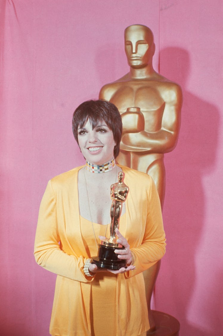 Liza wears a gold ensemble, holds Oscar