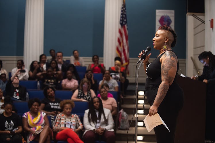 Entrepreneur Shelly Bell stands in front of a microphone in an auditorium, speaking to a crowd of mo...