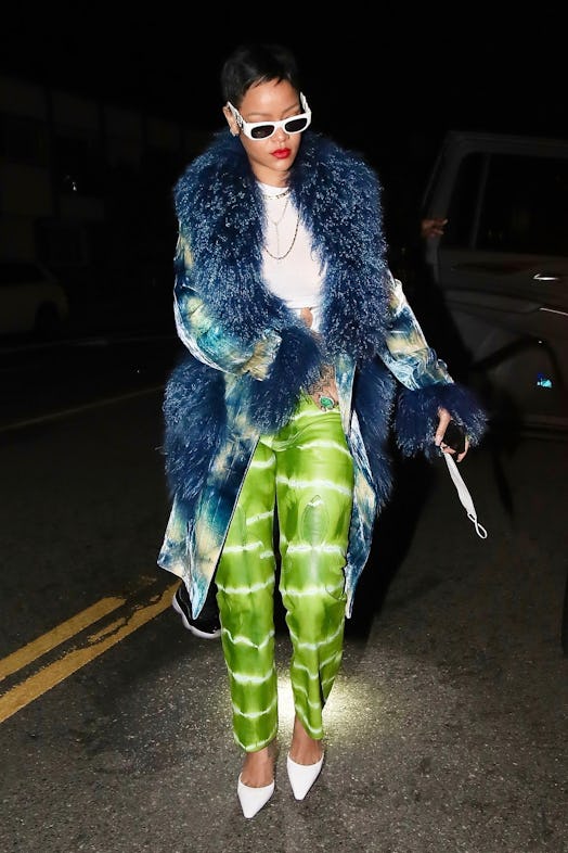 Rihanna with short hair wearing a blue jacket and green pants