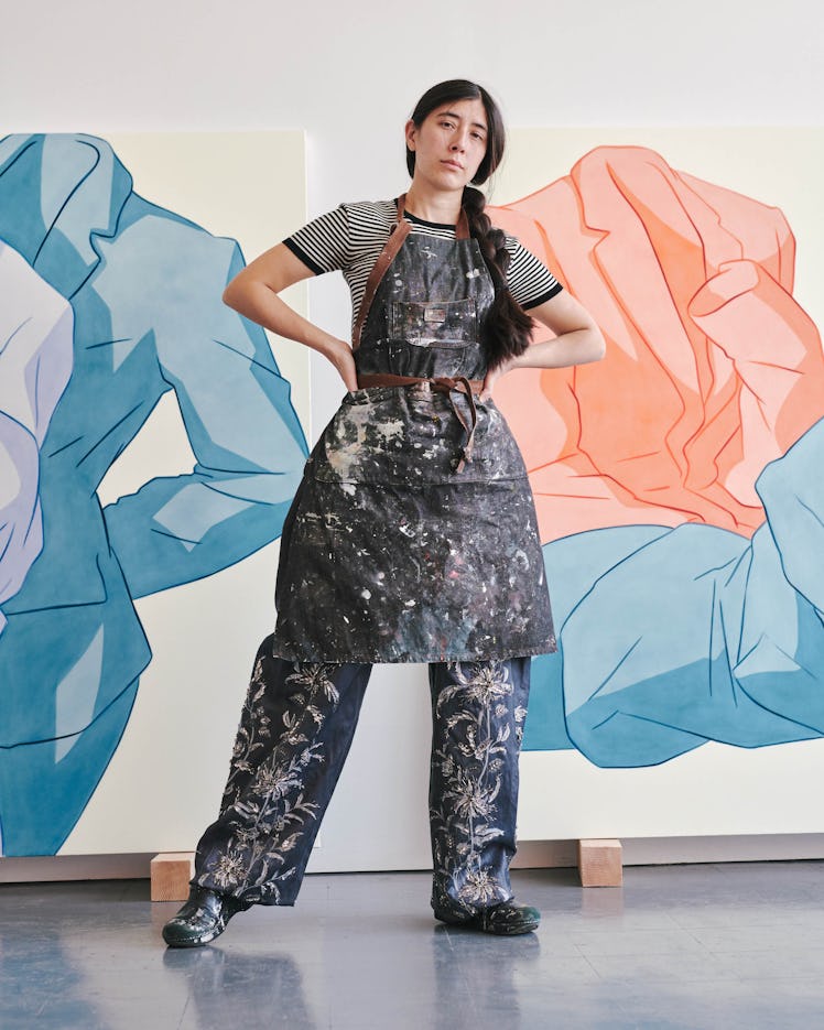 Ivy Haldeman Louis Vuitton T-shirt and pants; her own apron and shoes in front of two paintings.