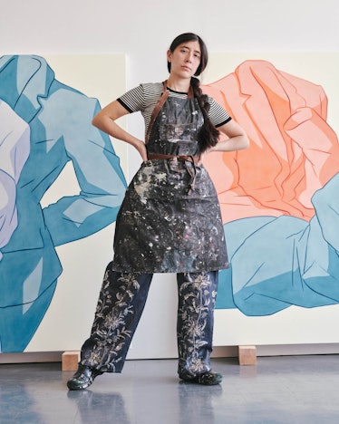 Ivy Haldeman Louis Vuitton T-shirt and pants; her own apron and shoes in front of two paintings.