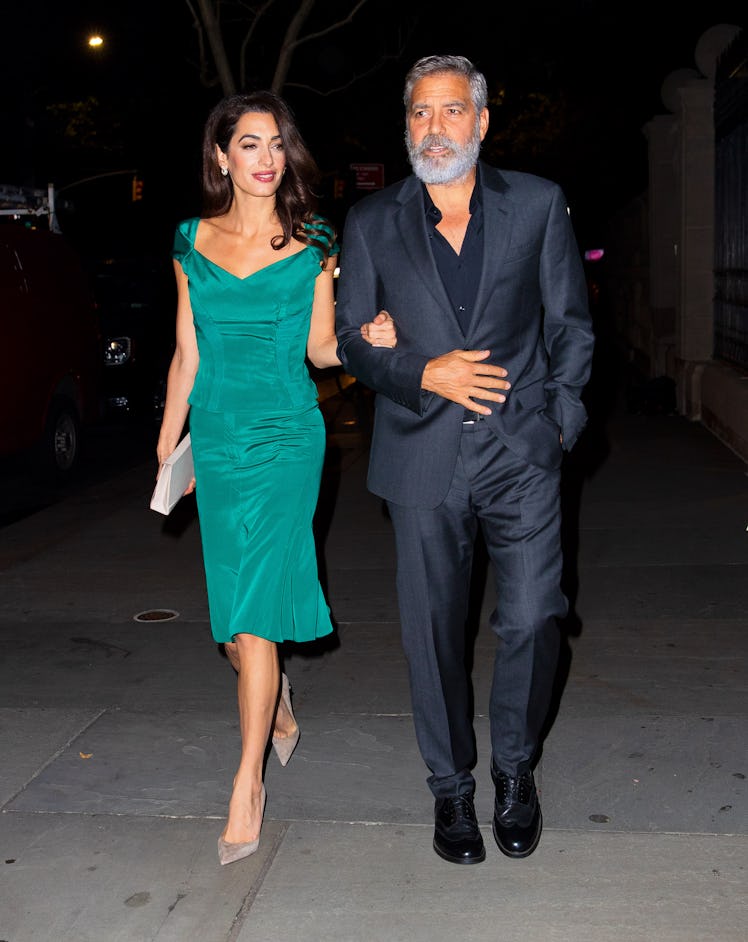 Amal Clooney in a green dress, George Clooney in a navy suit wearing a big beard