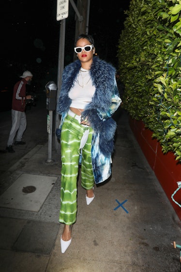 Rihanna wearing a colorful outfit sporting her iconic Pixie cut and white glasses to match her white...
