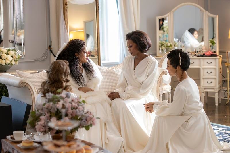 Four of the women from FX's Pose sitting and looking at each other in white gowns.