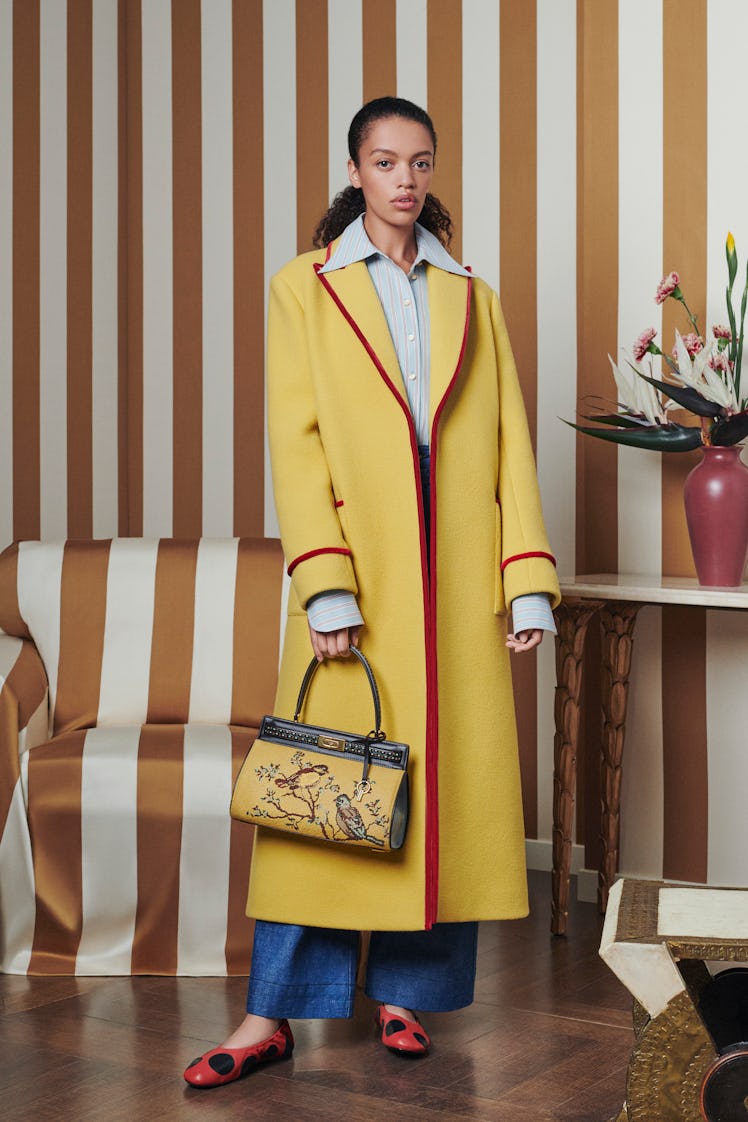 Model posing for a photo while wearing a yellow Tory Burch coat