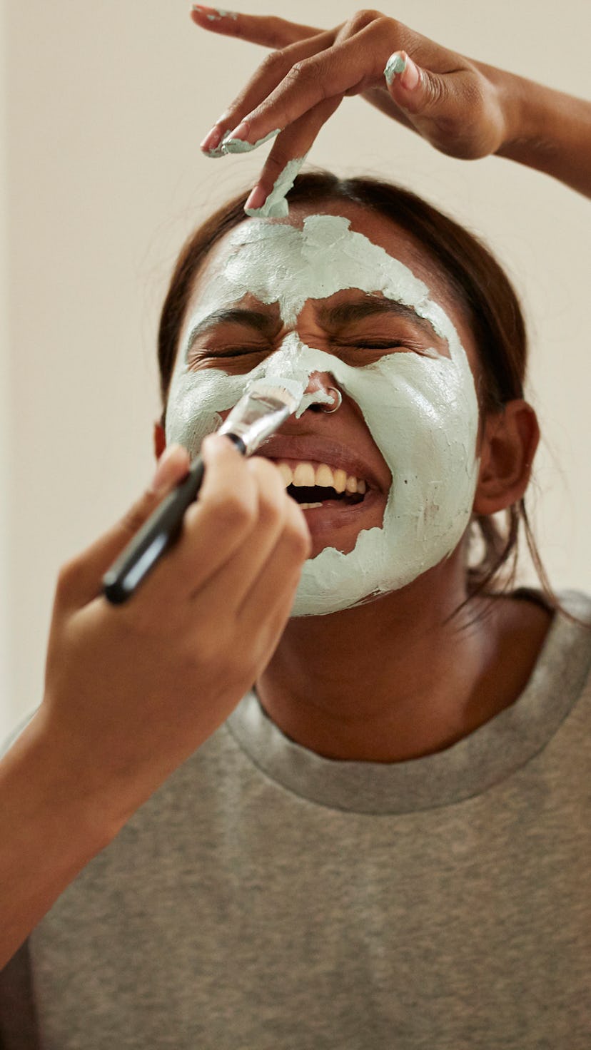 Young woman getting a facial from her friends in her spa-like bathroom.