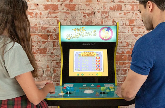 Two people playing Arcade1Up's The Simpsons cabinet video game