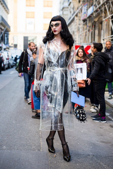 Violet Chachki in pin-up style in a black dress and a see-through rain coat street style outfit