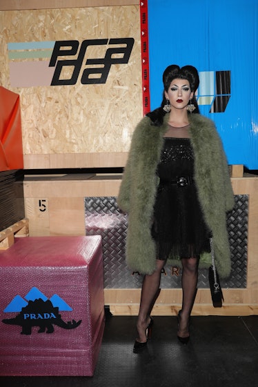 Violet Chachki in pin-up style in a black dress and a faux-fur coat at the Prada show