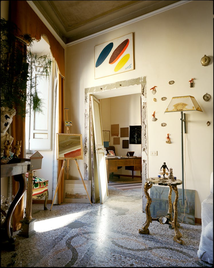 a living room in Rome with art and a hand painted lamp visible