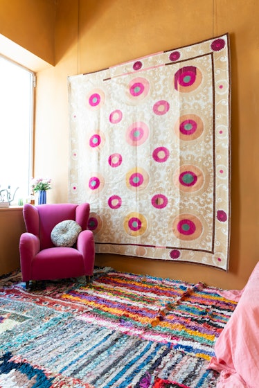A Suzani from the 1960s hangs behind a pink velvet armchair from the ‘50s. 
